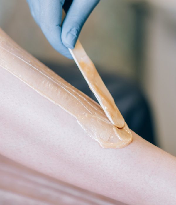 The specialist depilates the hair with wax on the leg